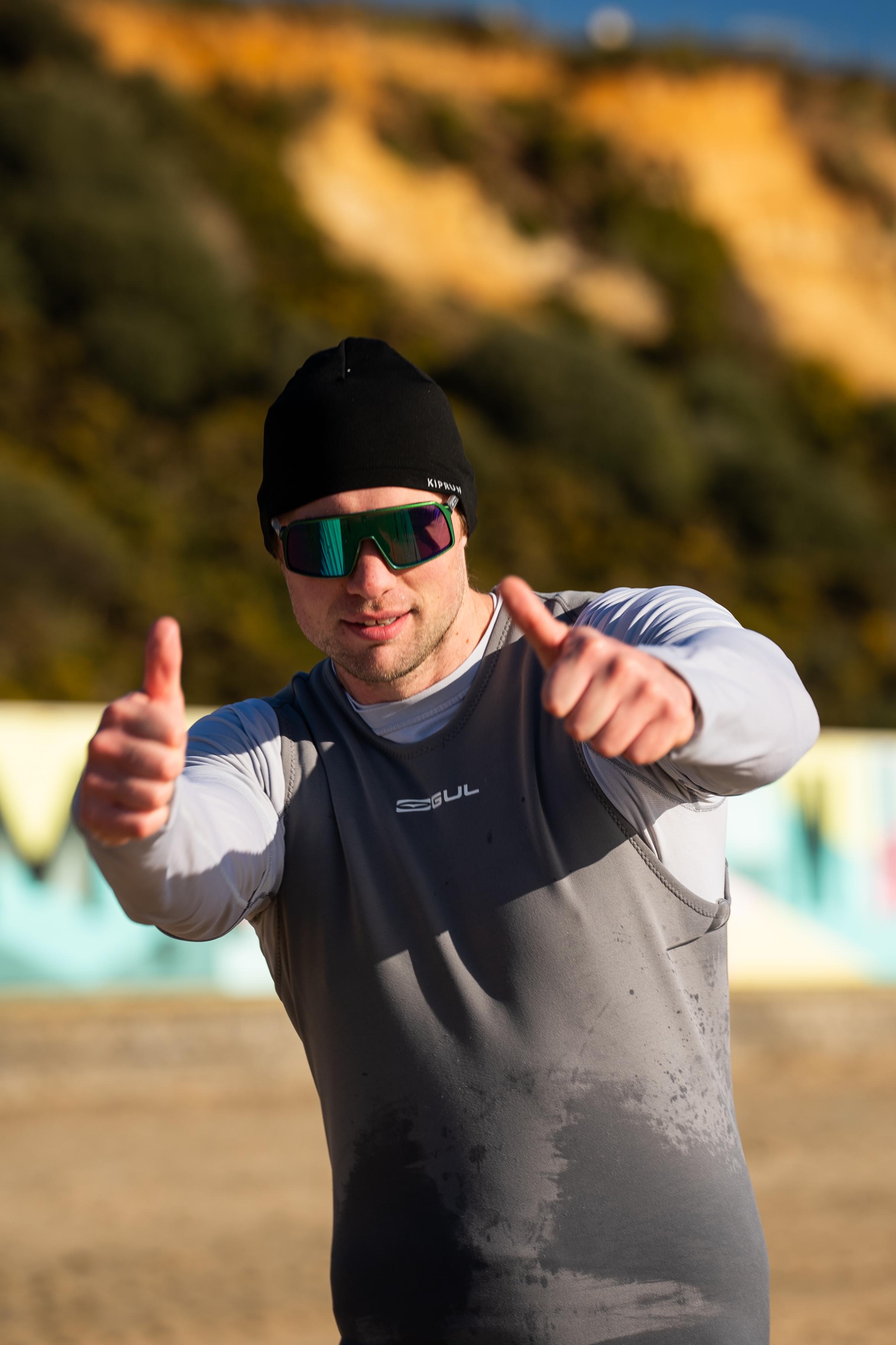 Phil Clapp sprinting on the beach and rowing in coastal sprint format while wearing a wetsuit – combining land speed and rowing strength for beach sprint performance.